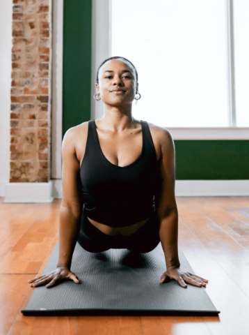 Uptown Yoga instructor KB Baldwin demonstrating Upward-Facing Dog, offering a non-competitive, safe space for former athletes to focus on personal health in Dallas.