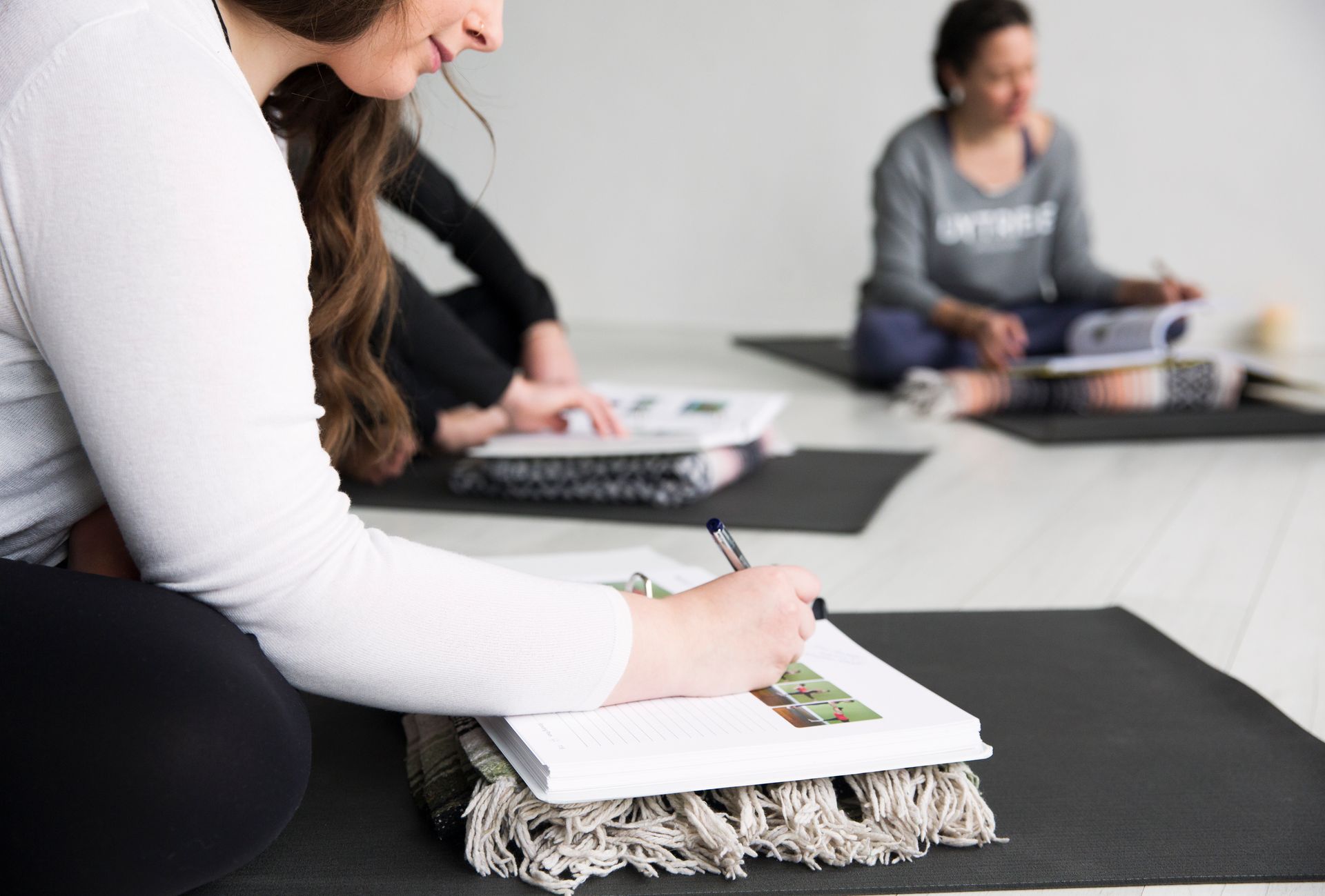 Yoga trainees sit on mats and take notes in their 250-page training manuals during the lecture.