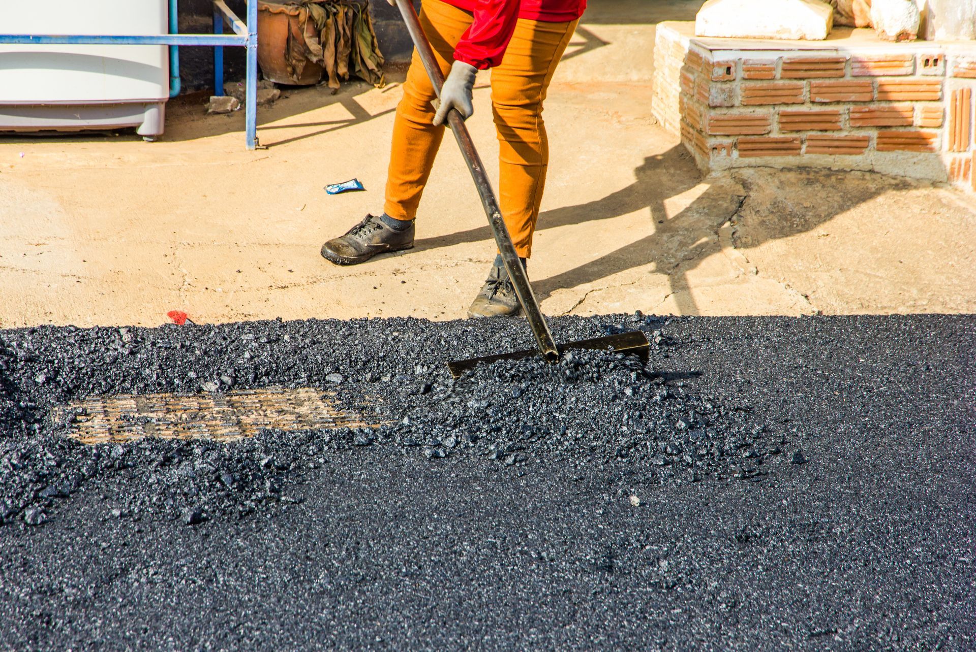 A worker is leveling the asphalt. A worker is leveling the asphalt.