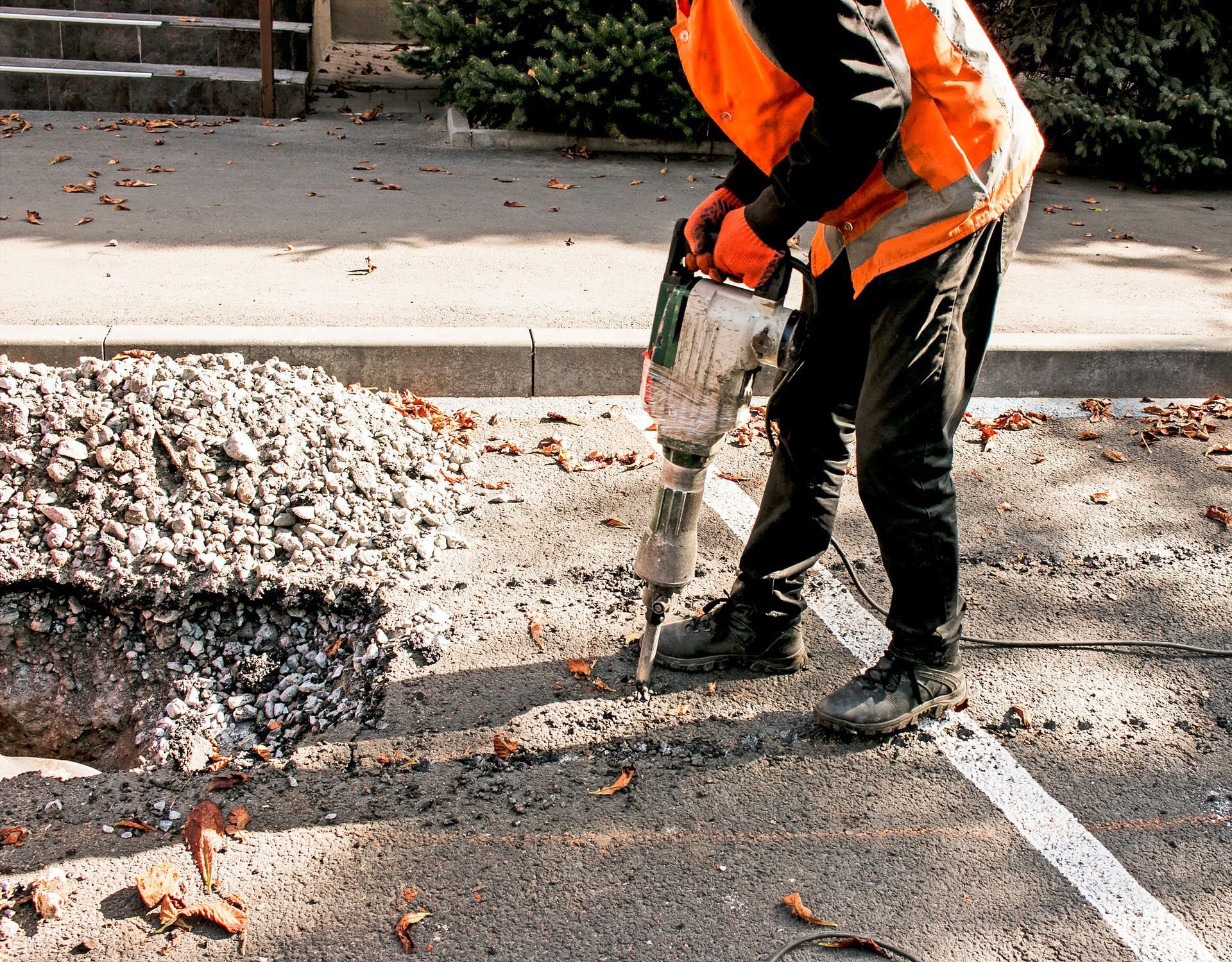 A Man Is Using A Hammer To Drill A Hole In The Ground | Middletown, OH | Affordable Paving Company