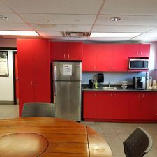 A kitchen with red cabinets and a stainless steel refrigerator.