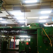 A green machine is sitting inside of a building in a factory.