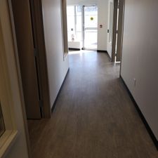 A long hallway with hardwood floors leading to a door.