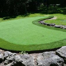 A green golf course surrounded by rocks and trees.
