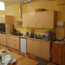 A kitchen with wooden cabinets , a sink , and a table.
