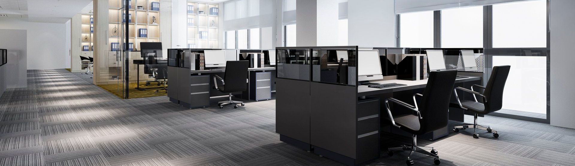 Modern office workspace with desks, chairs, and computers; bright natural light.