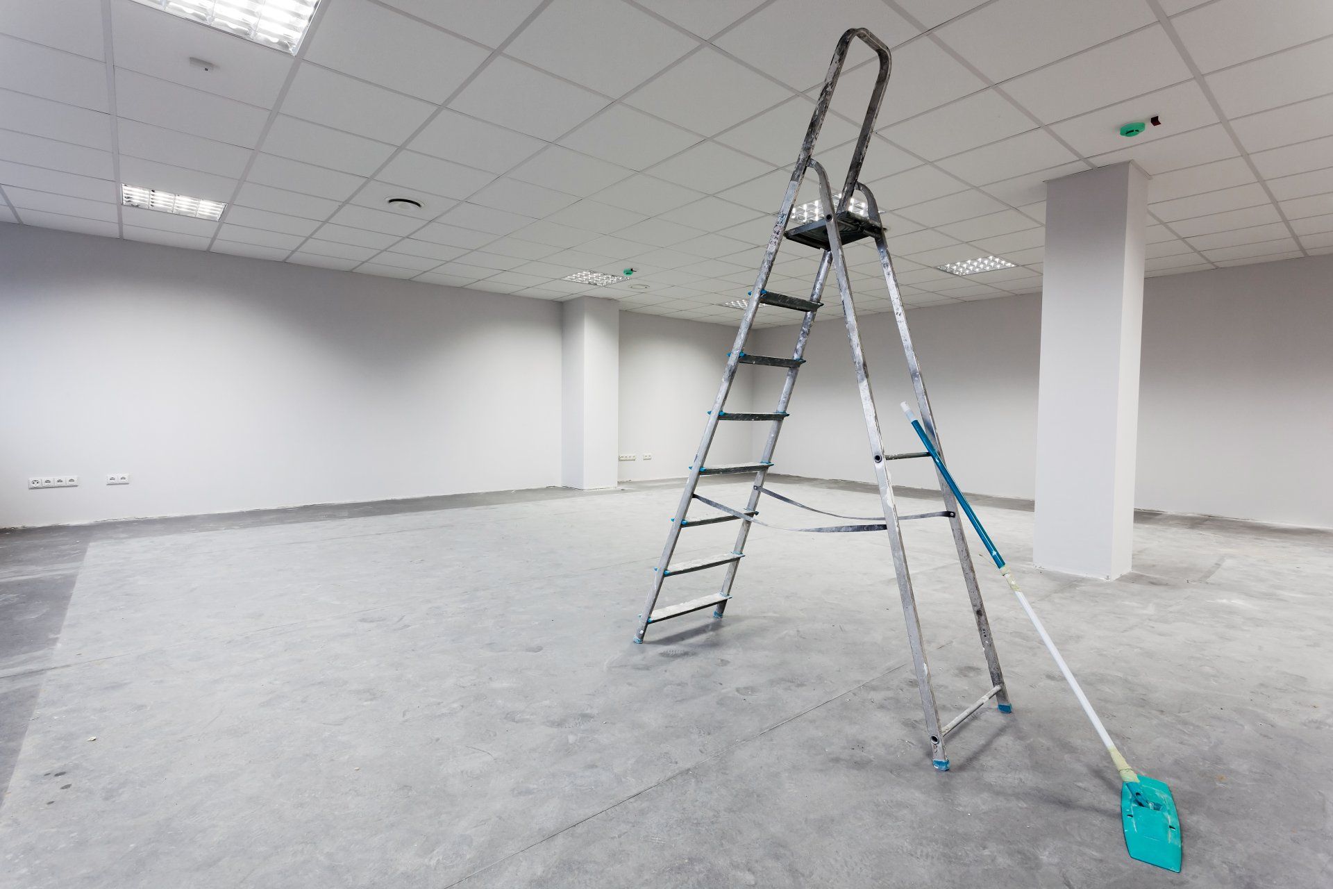 An empty room with a ladder and mop in it.