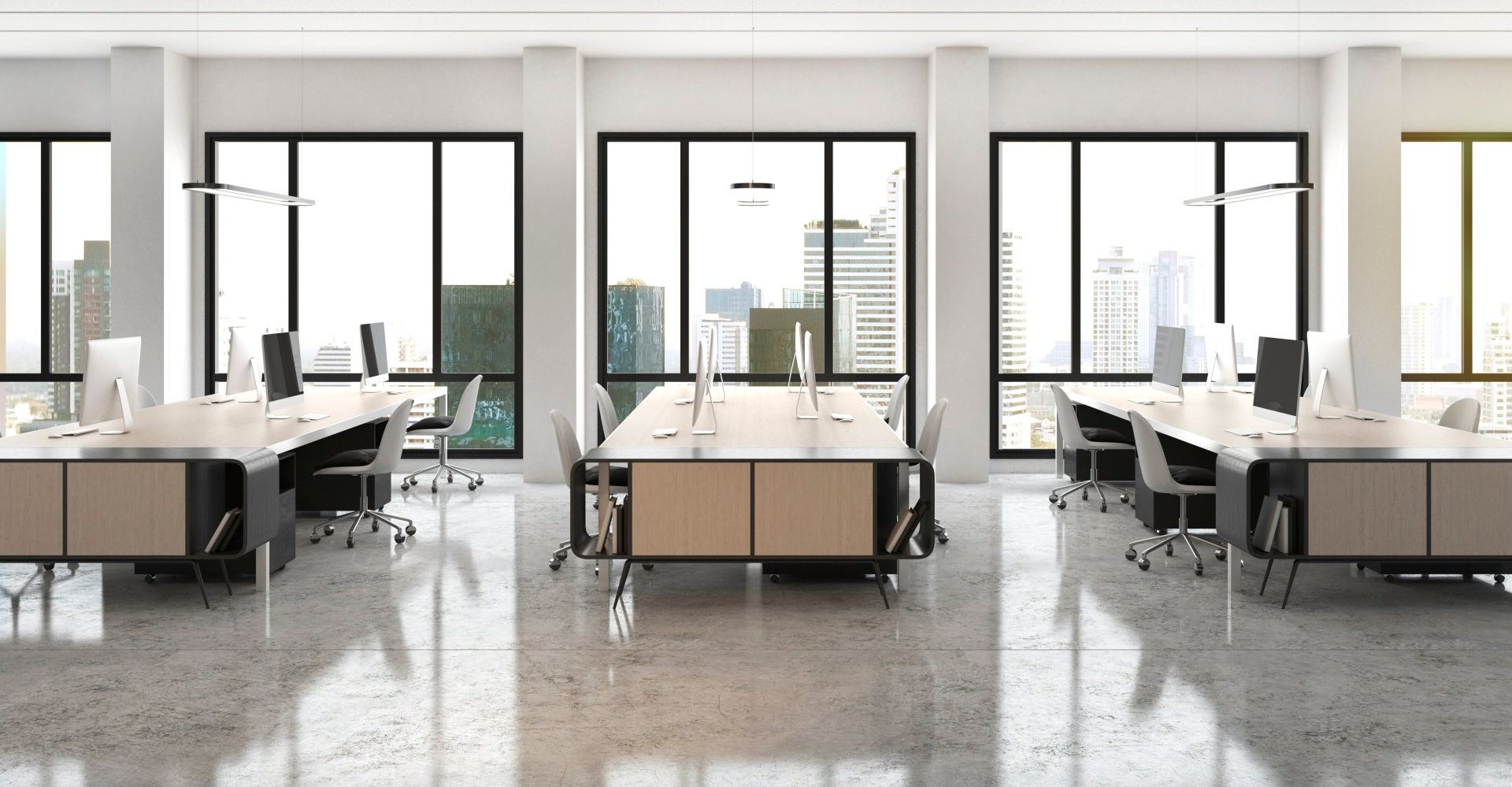 Bright, modern office with large windows overlooking a city, featuring multiple workstations.