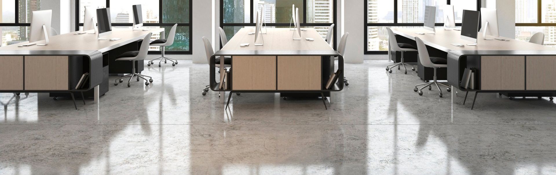 Modern office space with desks, chairs, and large windows overlooking city views.