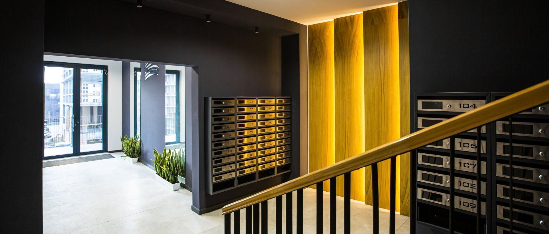 A staircase in a building with a yellow wall and a black railing.