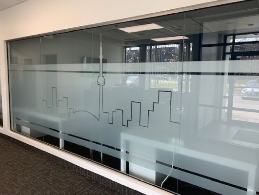 A glass wall with a drawing of a city skyline on it.