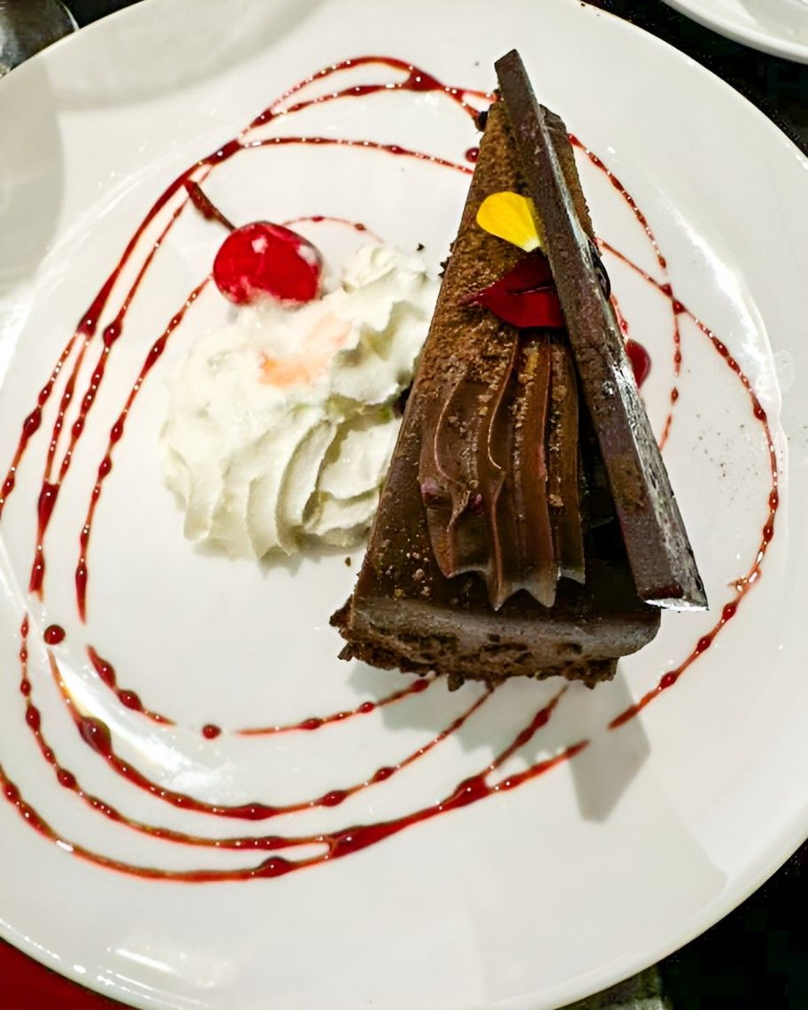 A Slice of Chocolate Cake With Whipped Cream and a Cherry on Top — Darwin Catering Company in Brinkin, NT