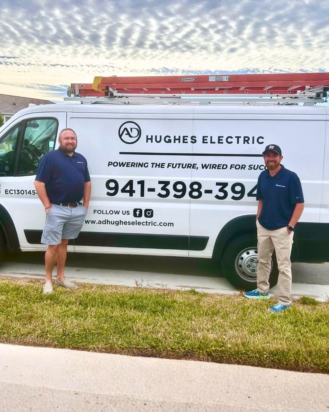 AD Hughes Electric work van with a ladder on the roof, parked on a residential street.