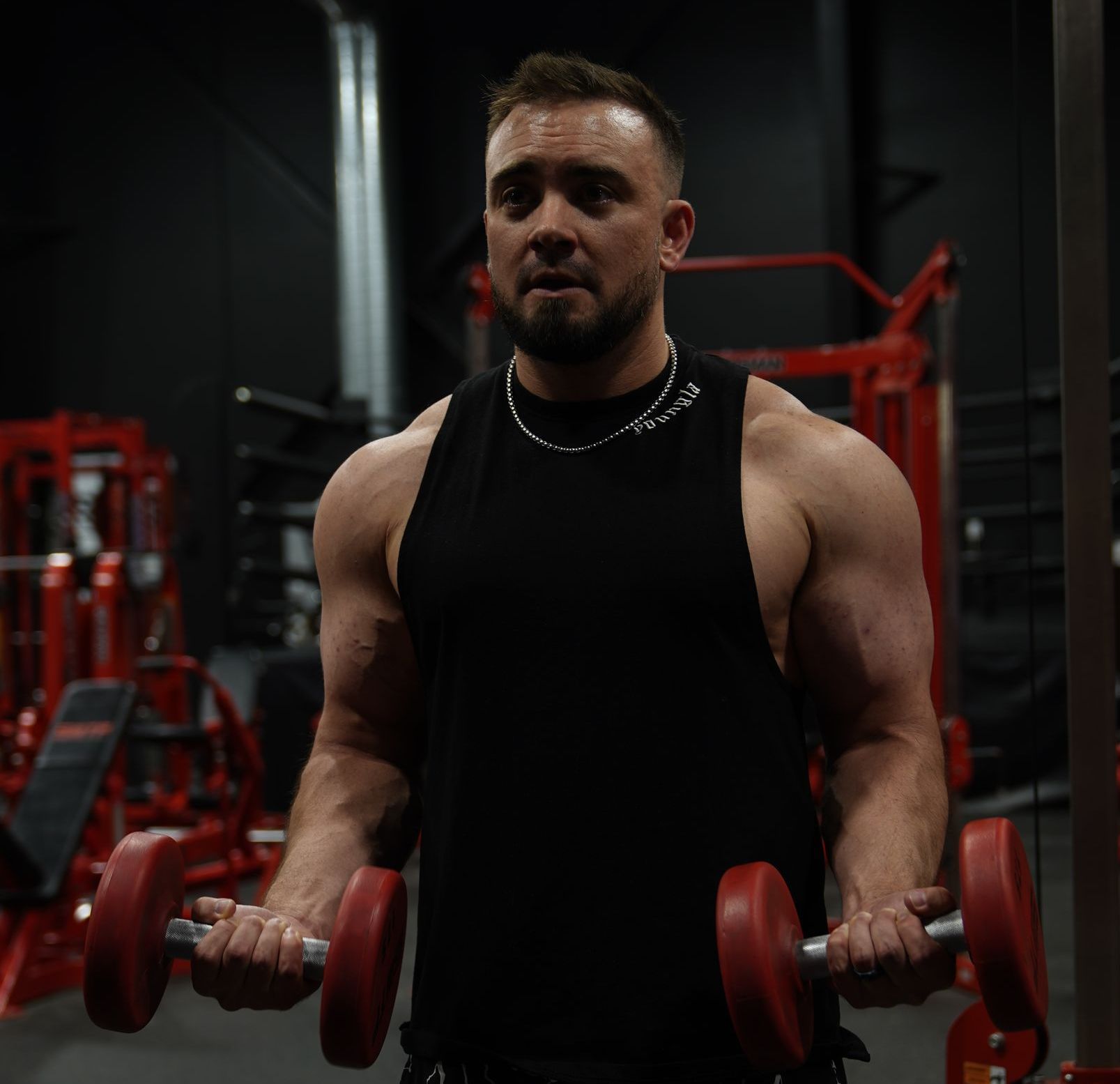 A man is lifting dumbbells in a gym.