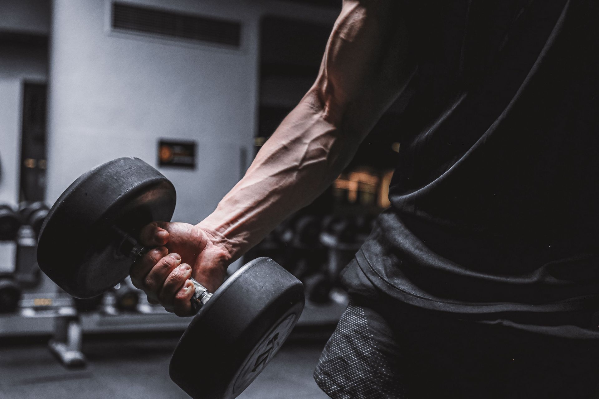 A man is sitting on a bench in a gym with his head in his hands.