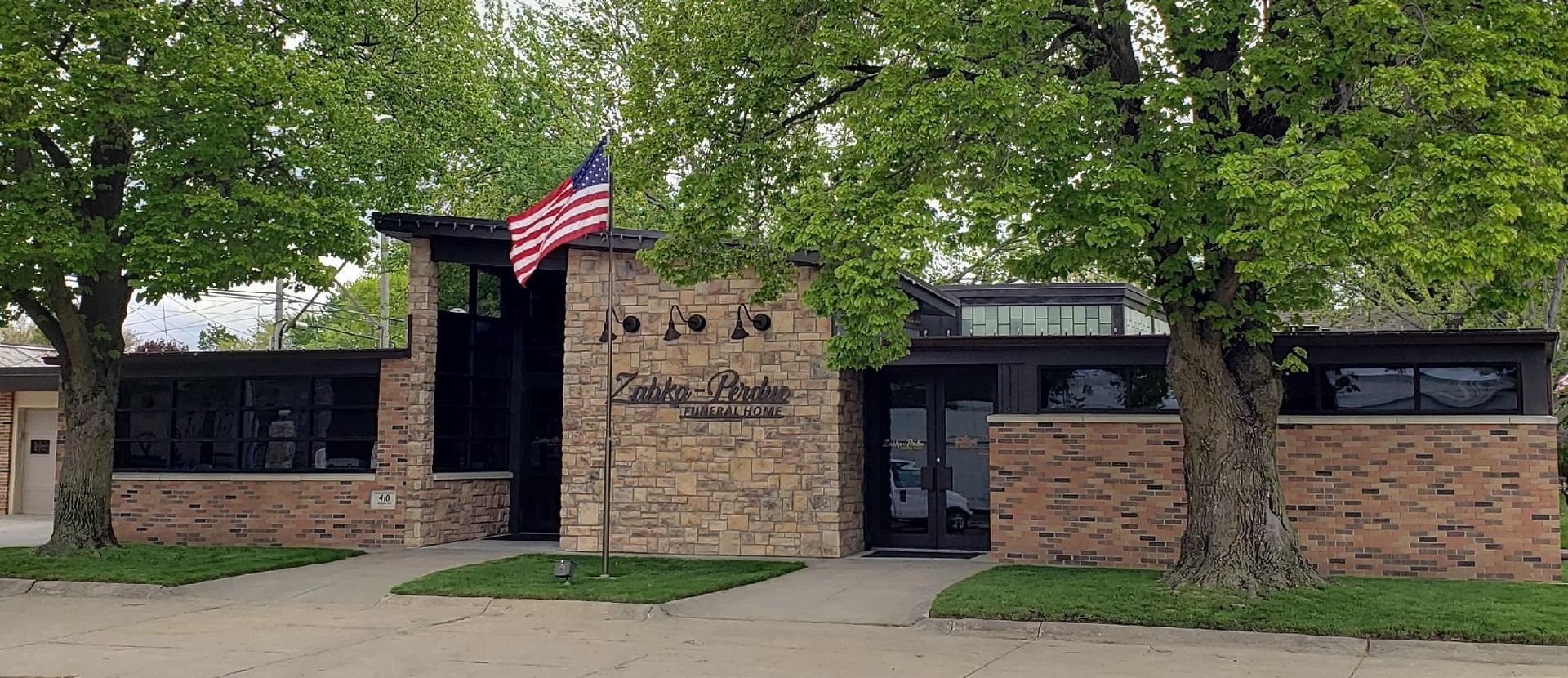 Stone building with an American flag. Trees flank the building.