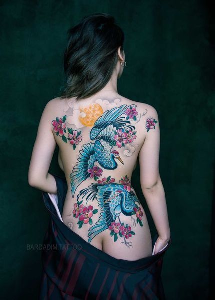 A woman has a tattoo on her back of a bird and flowers