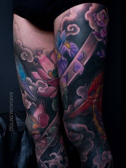 A woman has a tattoo of flowers and clouds on her leg.