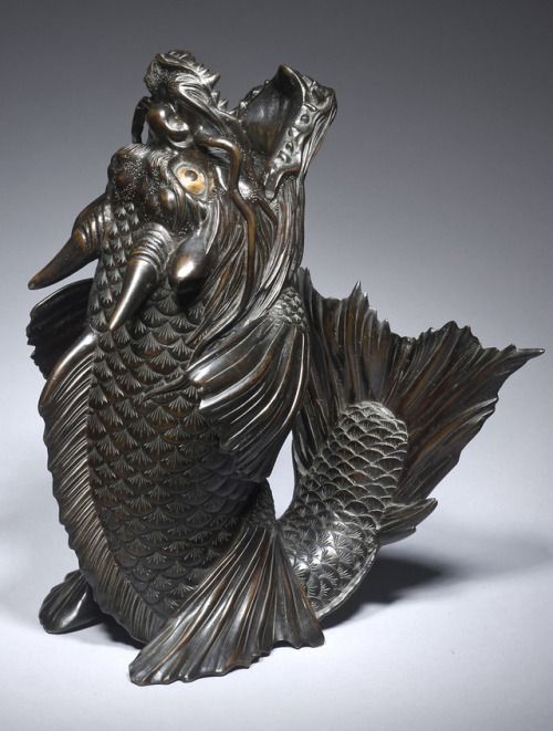 A statue of a koi-dragon is sitting on a white surface