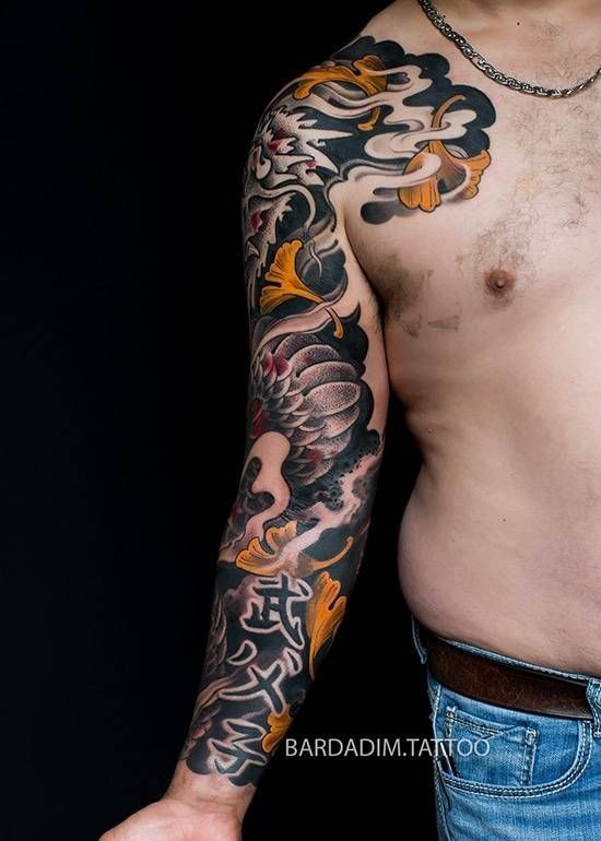 A shirtless man with a full sleeve tattoo on his arm.