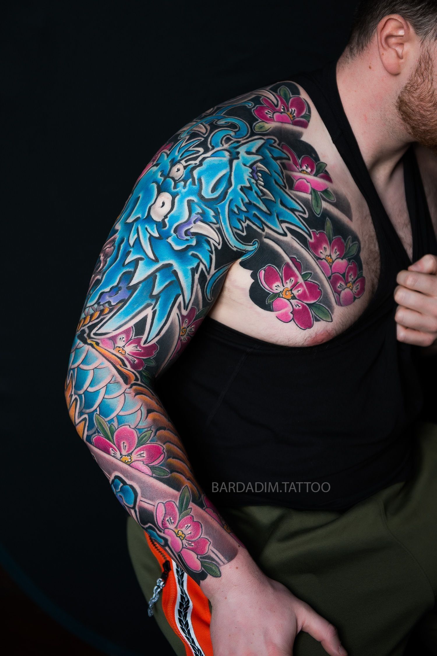 A man with a dragon tattoo on his arm and chest.