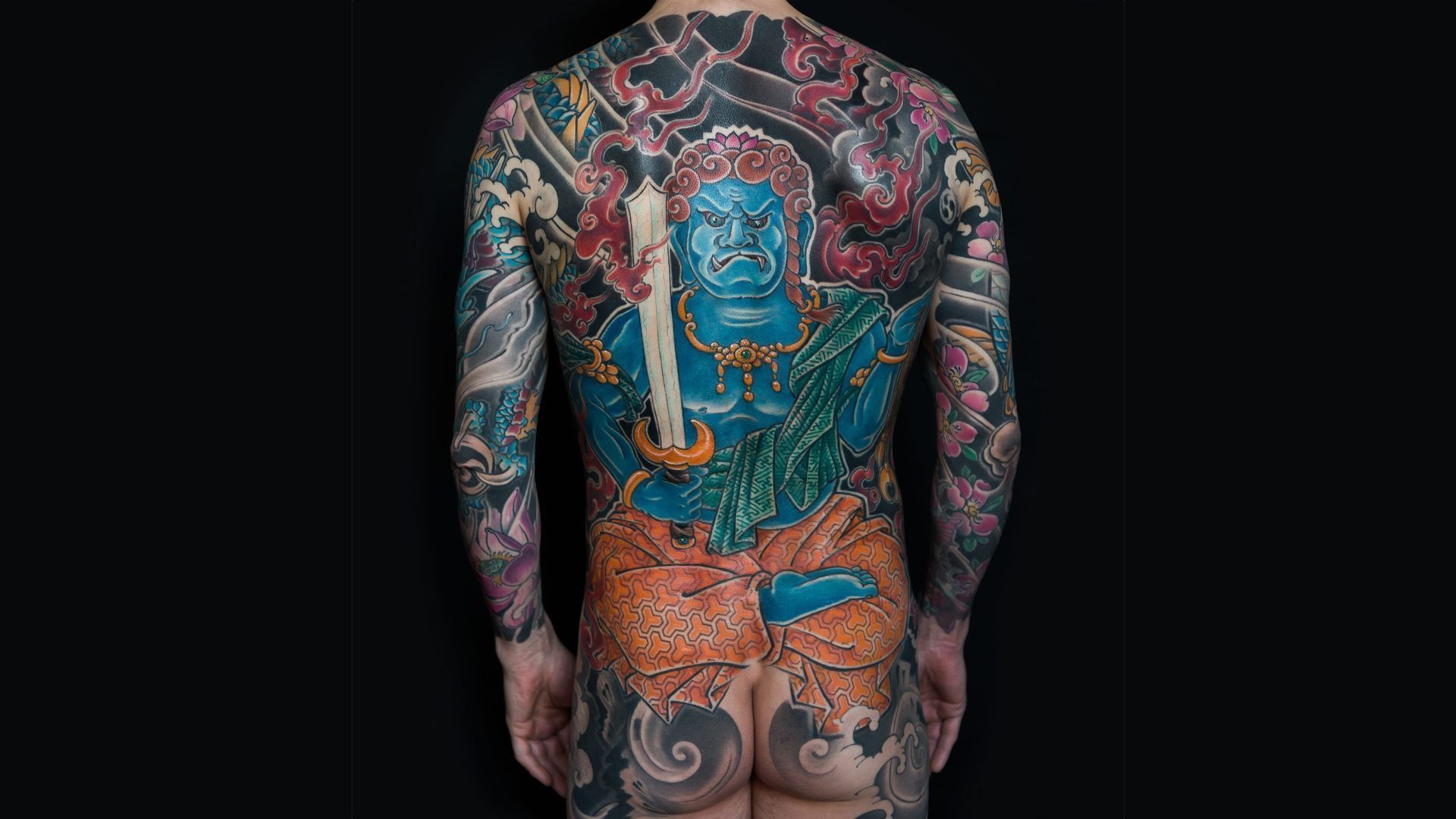 The back of a man with a lot of tattoos on his body.