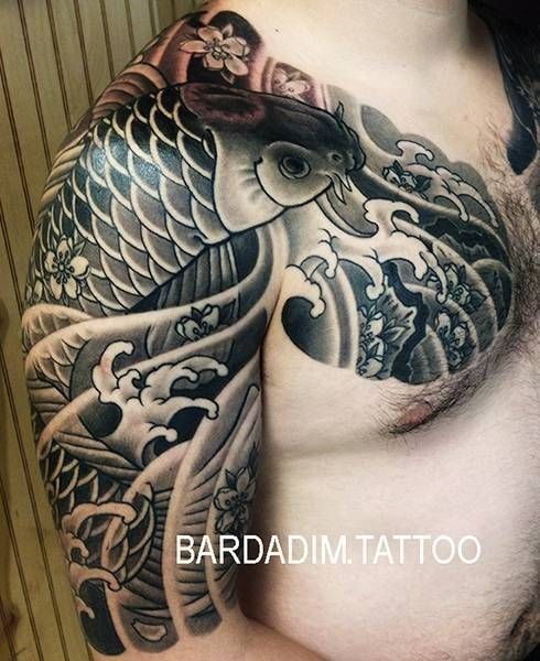 A man has a tattoo of a fish on his chest and shoulder