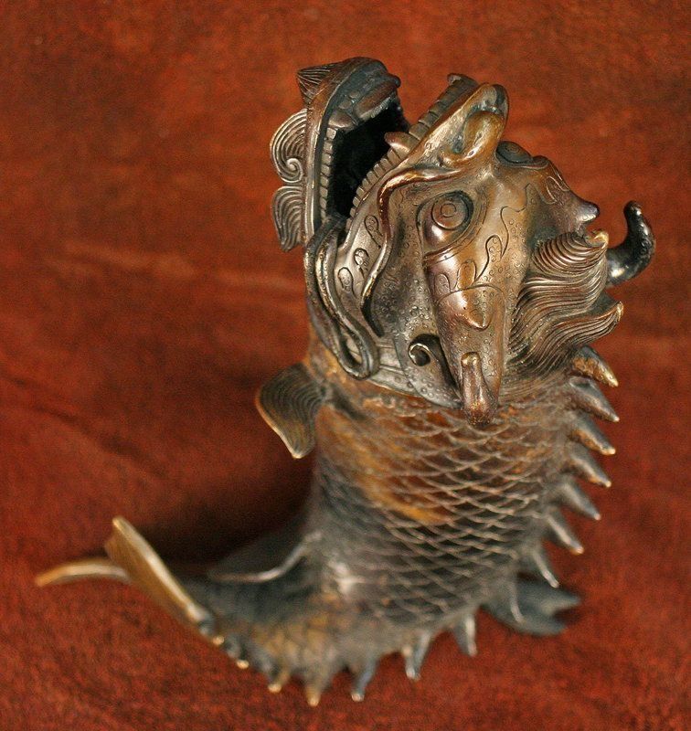 Bronze mythical sea creature sculpture with open mouth.