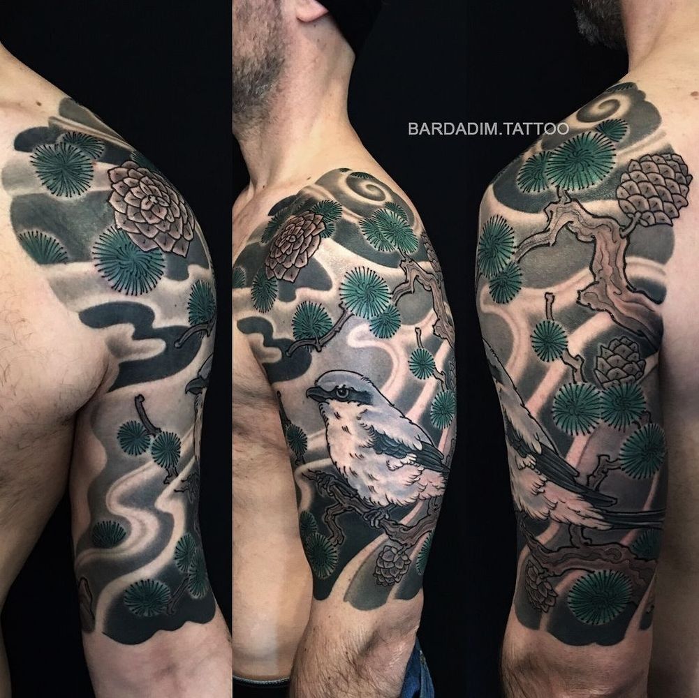 Tattoo of a bird perched on a branch, surrounded by pine needles and swirling grey clouds on a man's arm.