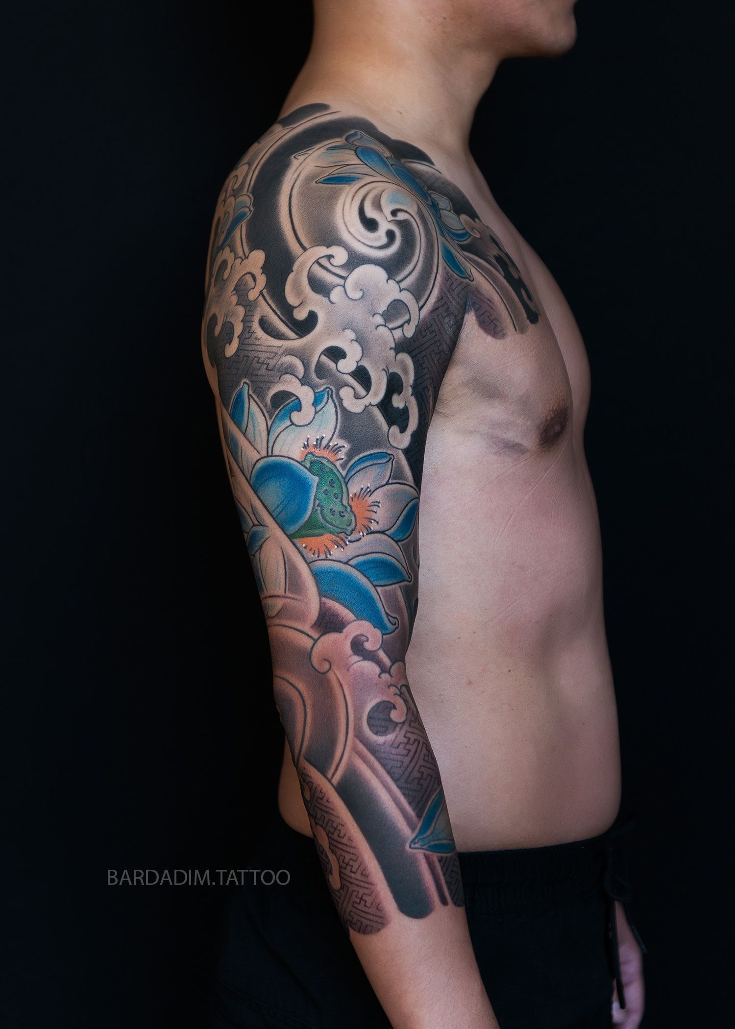 Side view of a person with a large colorful tattoo sleeve showing Lotuses and sayagata pattern