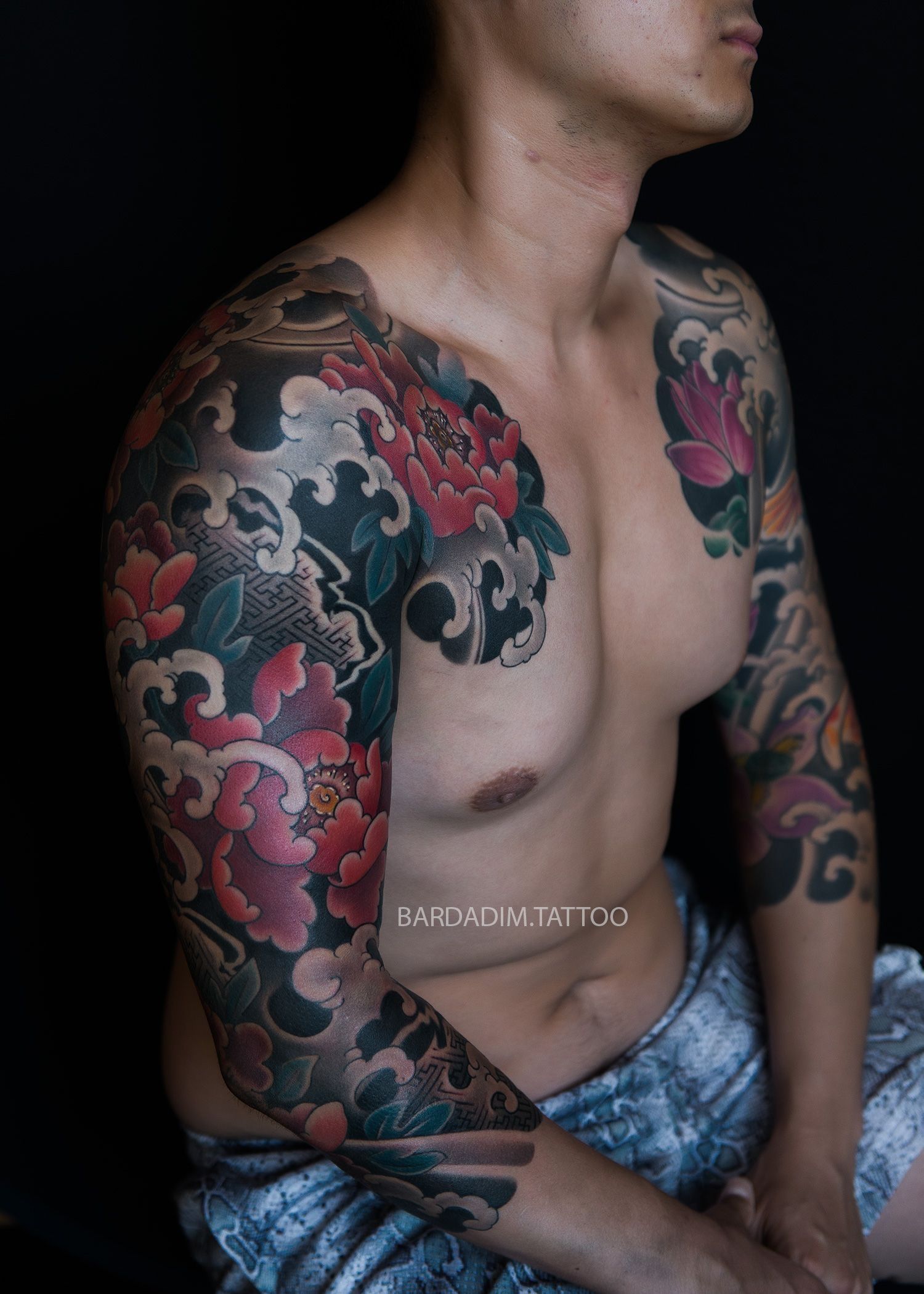 A shirtless man with a lot of tattoos on his arms and chest.