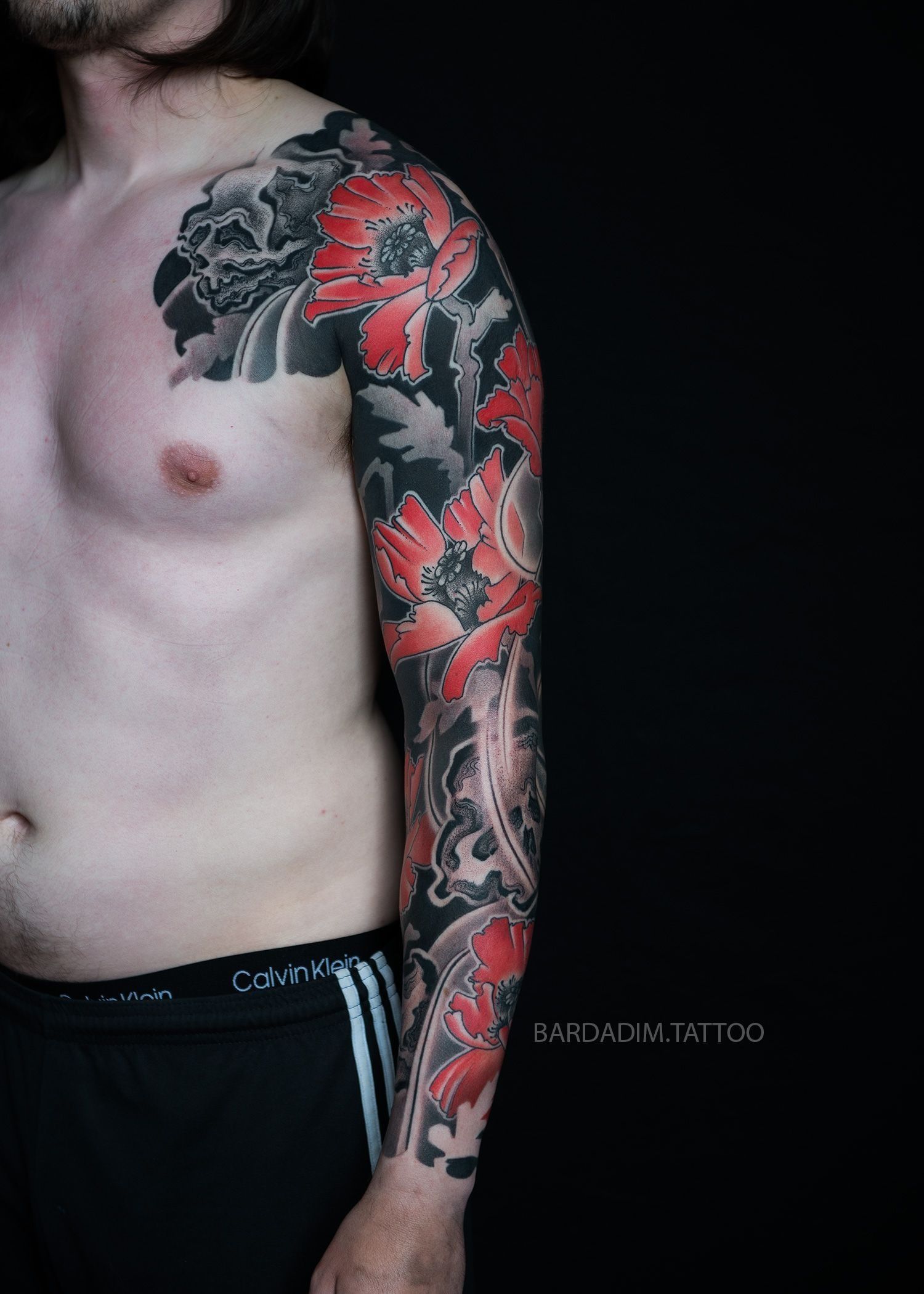 A man with a full sleeve tattoo on his arm and chest.