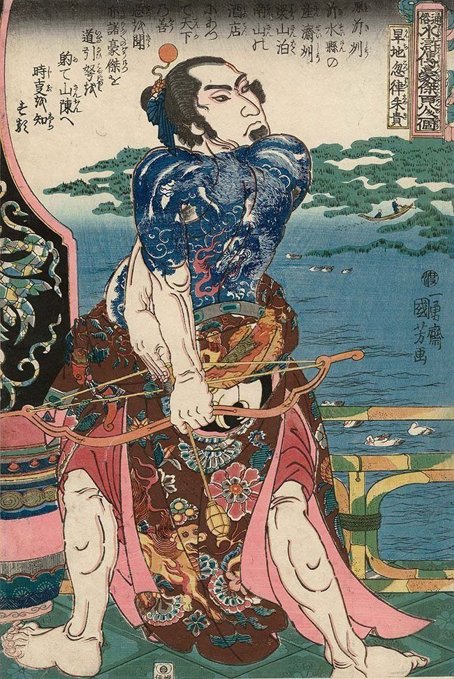 Man with full-body tattoos aims a bow and arrow, against a seascape background.