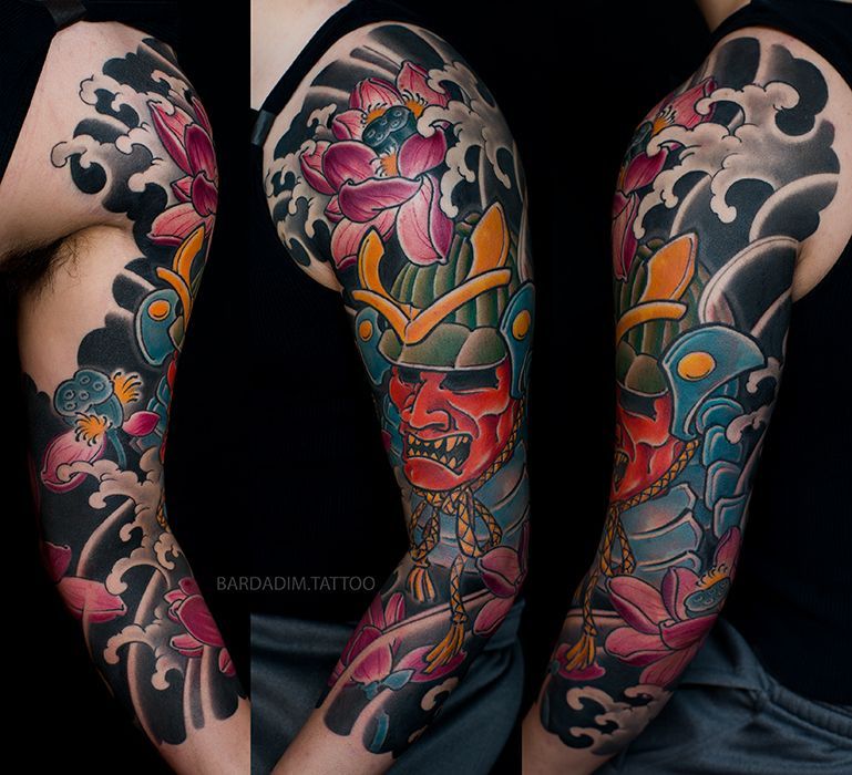 Colorful Japanese-style sleeve tattoo on arm: red samurai mask, lotus flowers, and swirling waves on a black background.