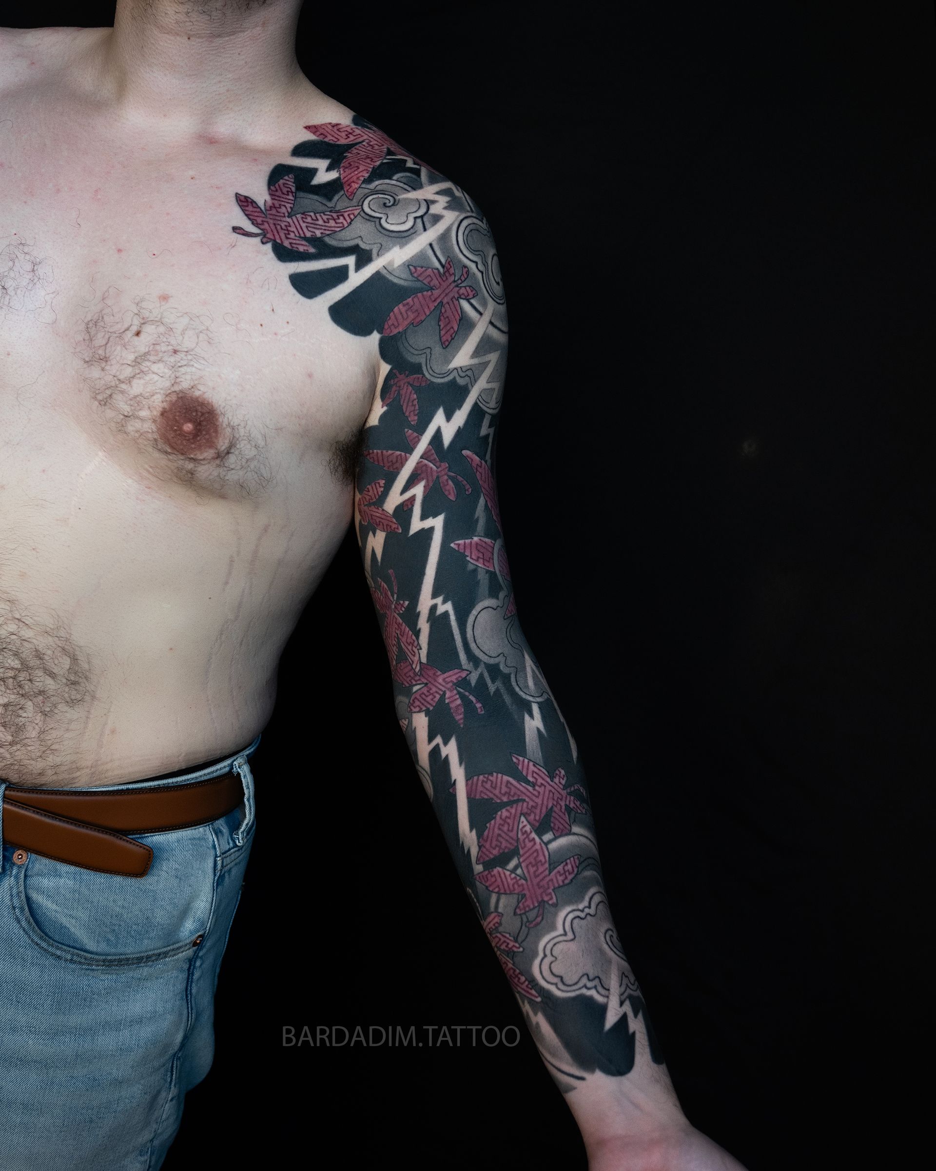 Front view of a red maple, storm cloud and lightning full sleeve in traditional Japanese irezumi, running from the arm onto the chest.