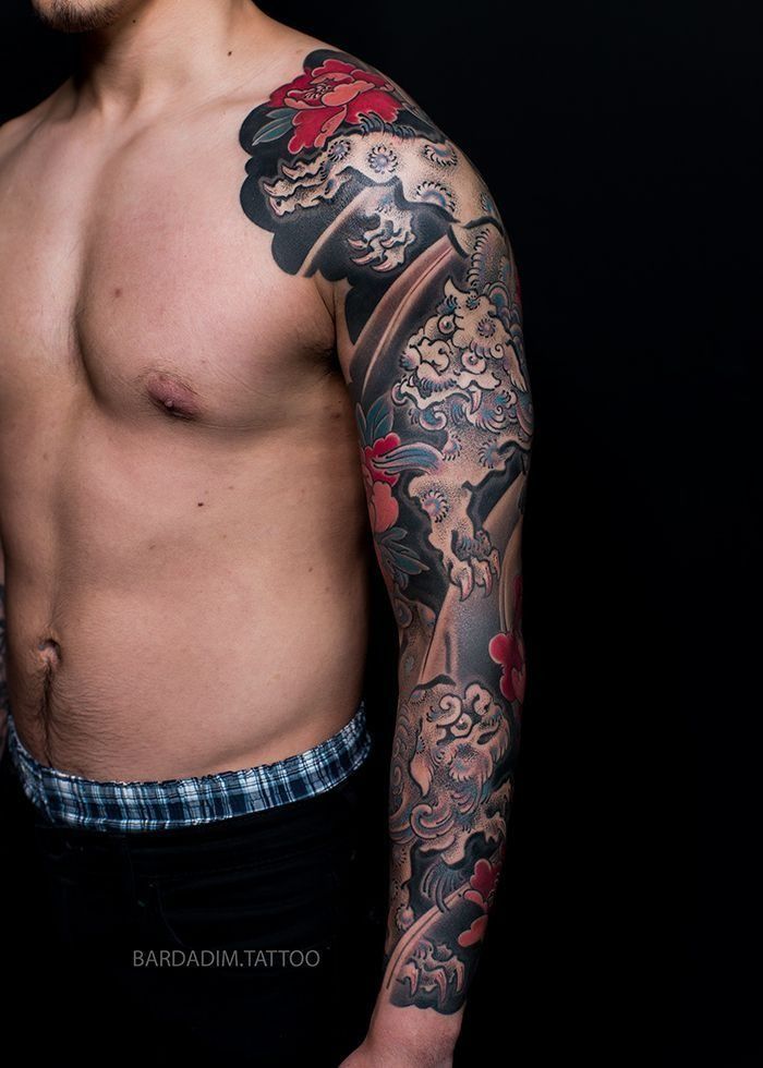 A shirtless man with a full sleeve tattoo on his arm.