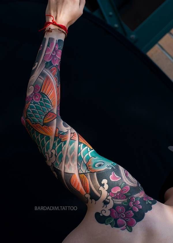 Colorful koi fish and flowers tattoo on a person's arm.