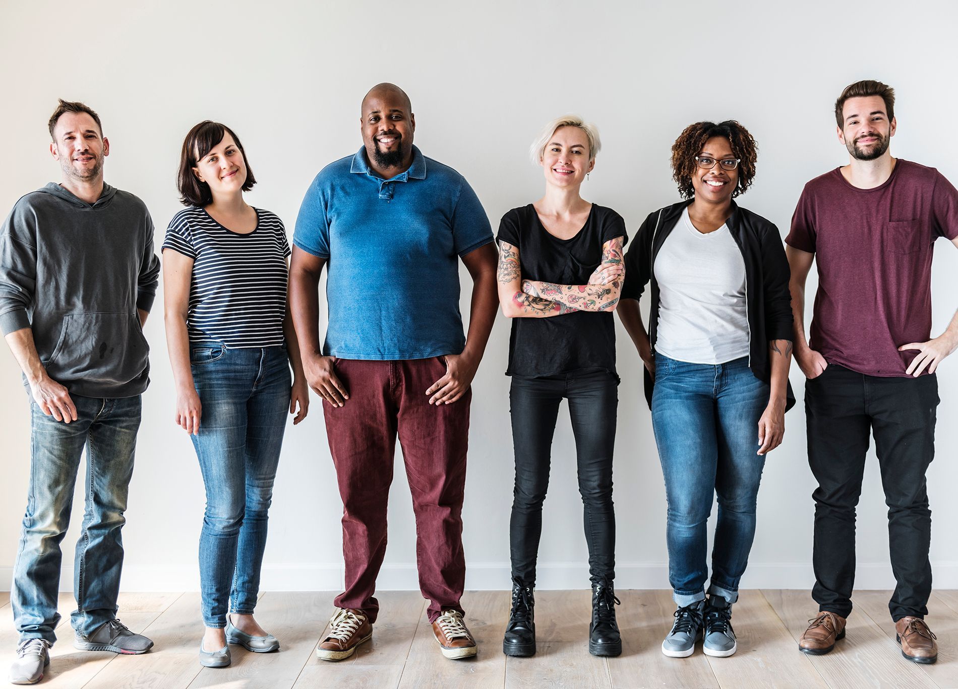 Group of people smiling and posing against a white wall.