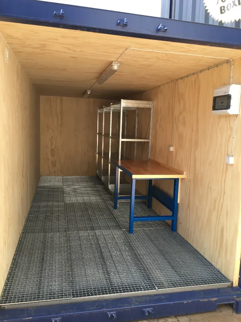 Blå skibscontainer modificeres med trærammer til dør- og vinduesåbninger.