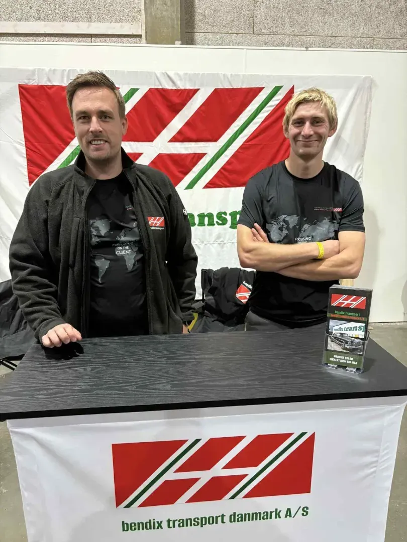 Two people stand behind a branded counter at a trade show, with the Bendix Transport Danmark logo displayed on a banner.