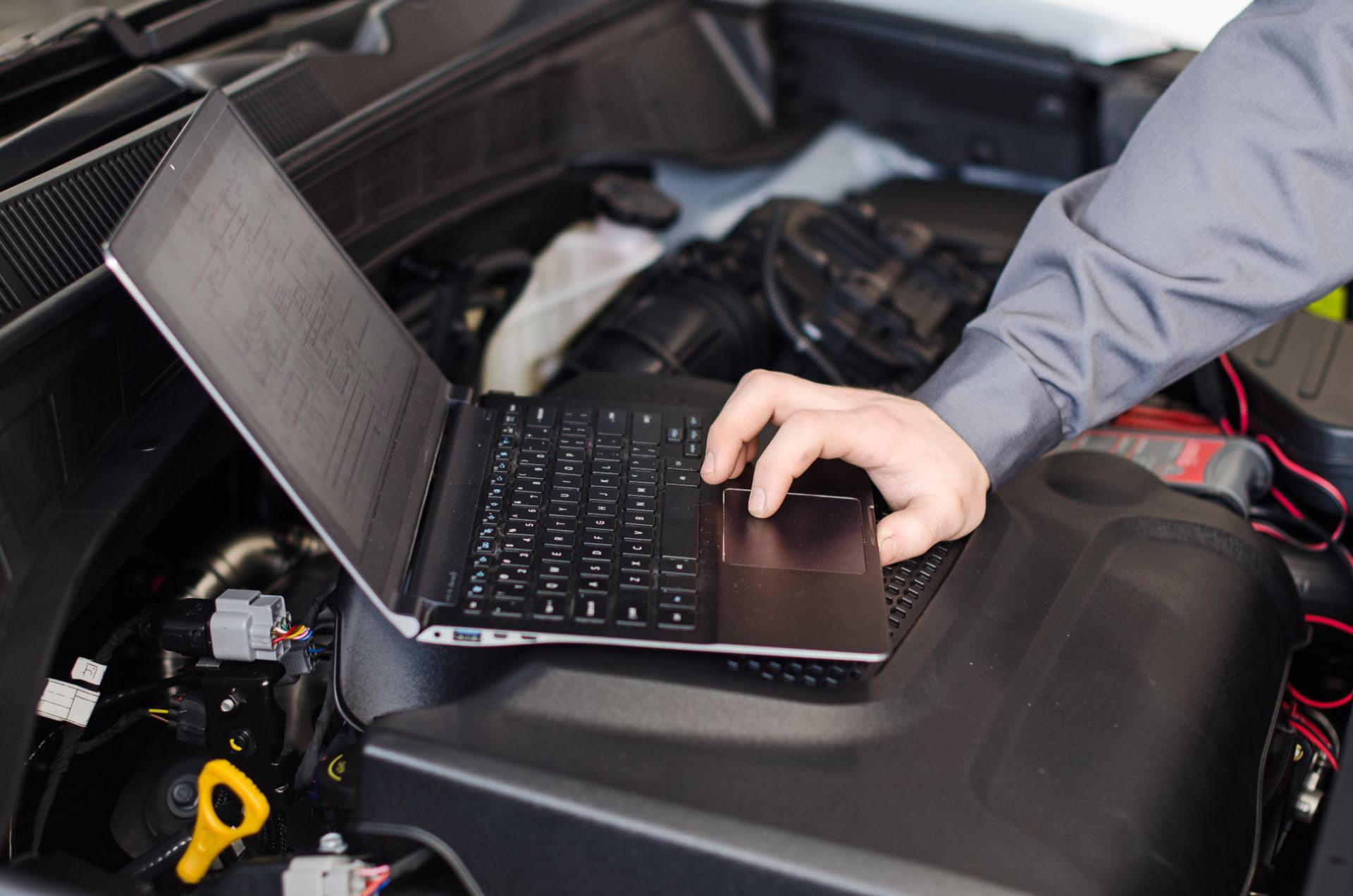Meccanico che utilizza un computer portatile per diagnosticare il motore di un'auto.