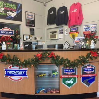 Reception desk at a car repair shop decorated for Christmas, displaying Technet logos and merchandise.