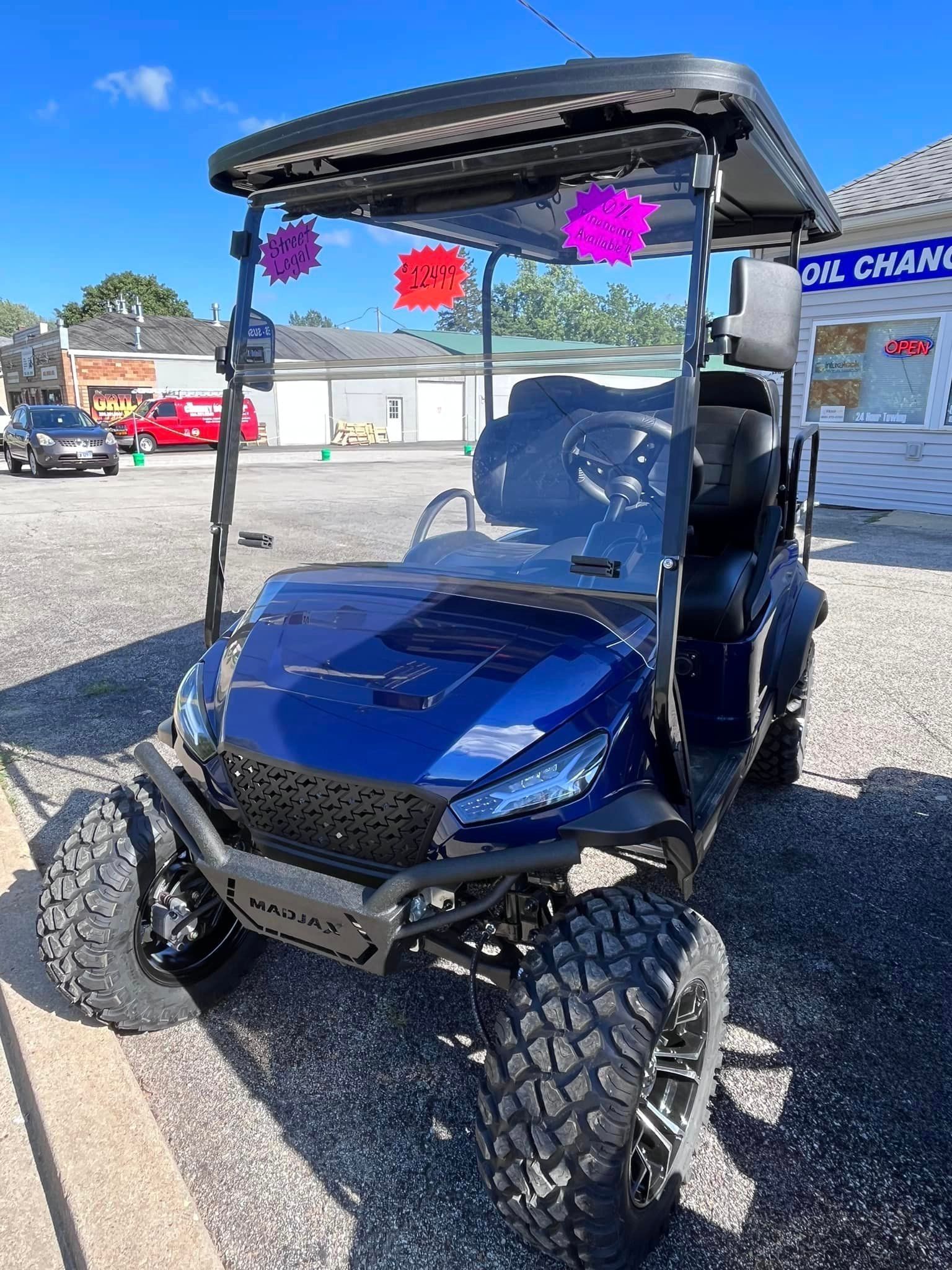 Blue golf cart with black tires parked outside a store on a sunny day.