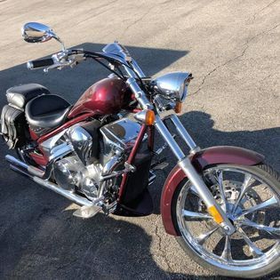 Burgundy motorcycle parked on pavement with chrome details.