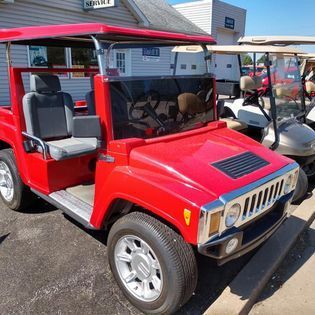 Red Hummer-style golf cart parked outside, sunny day.
