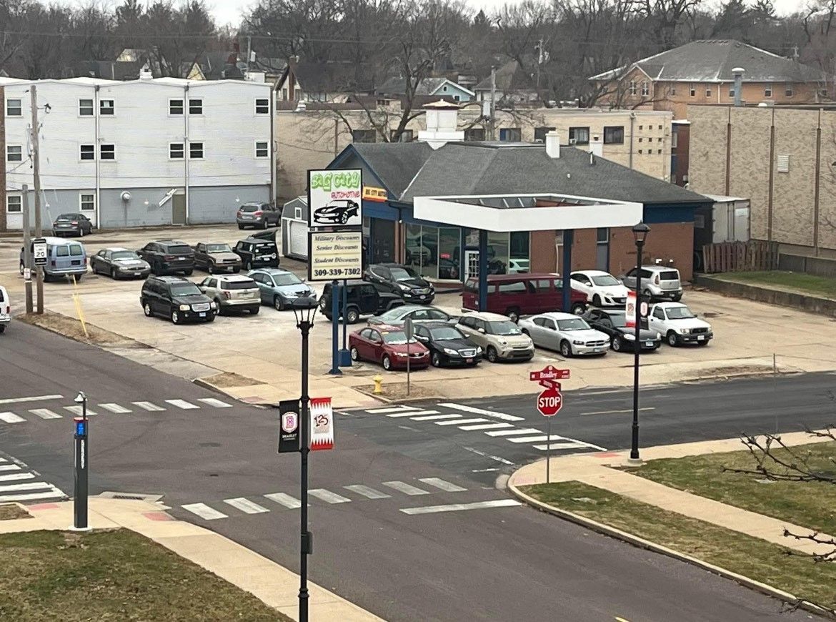 Cars parked at a gas station with a sign, located on a street corner.