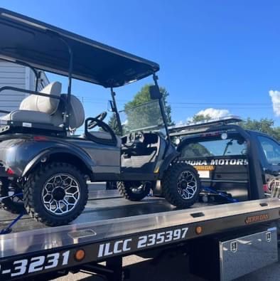 Golf cart on a tow truck, parked on a sunny day.