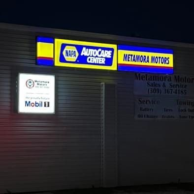 Illuminated sign for Metamora Motors, a NAPA AutoCare Center. Includes a Mobil 1 sign.