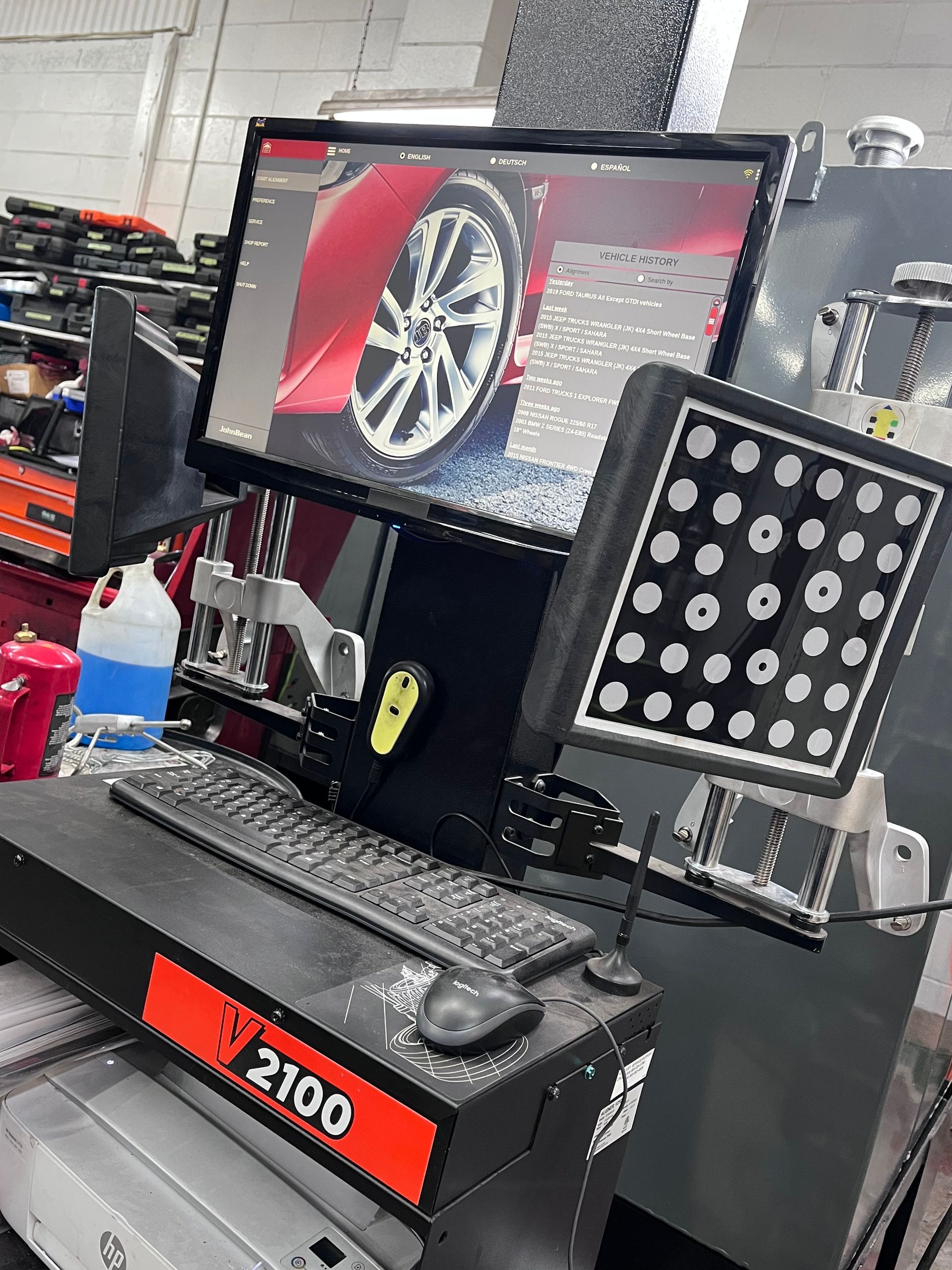 Wheel alignment machine displaying a car wheel on a screen in a garage.