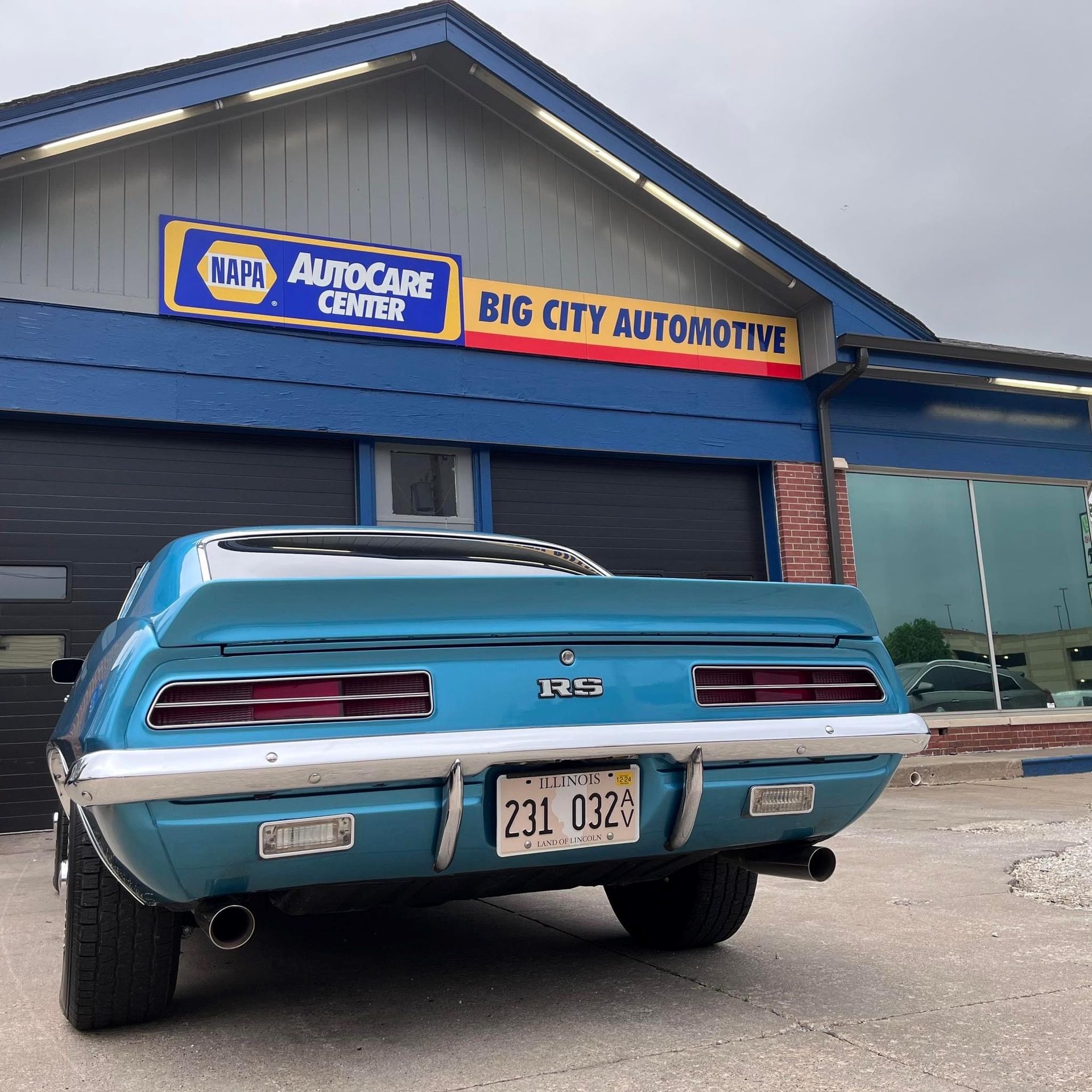 Blue classic car parked in front of Big City Automotive. NAPA AutoCare Center sign.